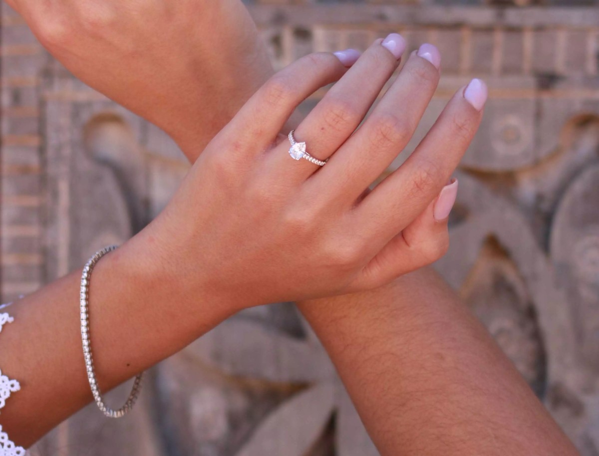  Une femme porte une bague de fiançailles en diamant de laboratoire et un bracelet en or blanc 18 carats. Bijoux éthiques et élégants signés Laveran Paris.